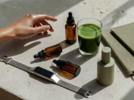 Curated wellness lifestyle flat lay with wearable tracker, supplement bottles, green smoothie, and skincare serum representing the longevity biohacking movement in 2026