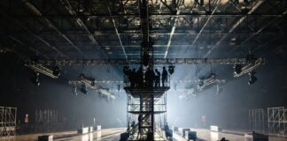 Behind the Scenes: What Fashion Week Production Costs Production crew setting up lighting rigs and staging inside a fashion week show venue, representing the behind the scenes costs of runway show production