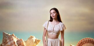 Celebrity Children Are Becoming Luxury Fashion’s New Generation of Campaign Stars Young woman in ivory eyelet ensemble on a dreamlike beach representing the Apple Martin Chloé campaign and the celebrity children fashion debate in luxury advertising 2026