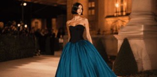 Chrissy Teigen wearing a strapless black corseted bodice and dramatic teal bubble skirt by Aisté Hong at the 2026 Gold Gala red carpet.