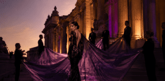 Madonna wearing a black lace Saint Laurent gown with a violet organza cape carried by seven attendants on the Met Gala 2026 red carpet steps.