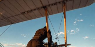 Mission: Impossible – The Final Reckoning Gives Tom Cruise a Franchise-Best Opening Cinematic shot of a figure gripping a biplane wing above a canyon at golden hour representing Tom Cruise's record-breaking stunts in Mission Impossible Final Reckoning