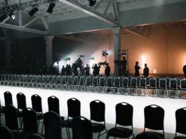 Empty New York Fashion Week runway with production crew preparing the venue before the show, illustrating how the NYFW schedule is built and sequenced