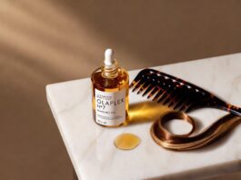 Olaplex No.7 Bonding Oil 30ml bottle on a white marble surface with a wide-tooth comb and glossy highlighted hair strand, editorial beauty product photography for a 2026 haircare review.