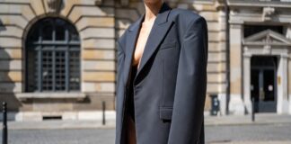 Fashion week attendee in ultra-short tailored shorts and oversized structured blazer on European pavement representing the micro shorts trend 2026 and the polarizing street style silhouette debate in luxury fashion