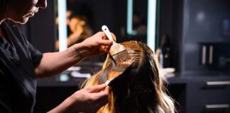 Why Celebrity Colorists Are Becoming Fashion’s Most Powerful Beauty Influencers Colorist applying rich warm hair color to a client in a luxury salon representing the celebrity colorist as brand phenomenon in 2026 and the rise of Tracey Cunningham Chris McMillan and Chase Kusero as hair industry beauty influencers