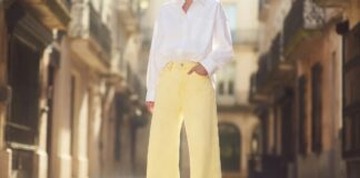 Fashion figure in butter yellow wide-leg pastel denim jeans with white oversized shirt on sunlit European street representing the pastel denim trend 2026 and the shift from indigo to soft pastel shades in summer street style
